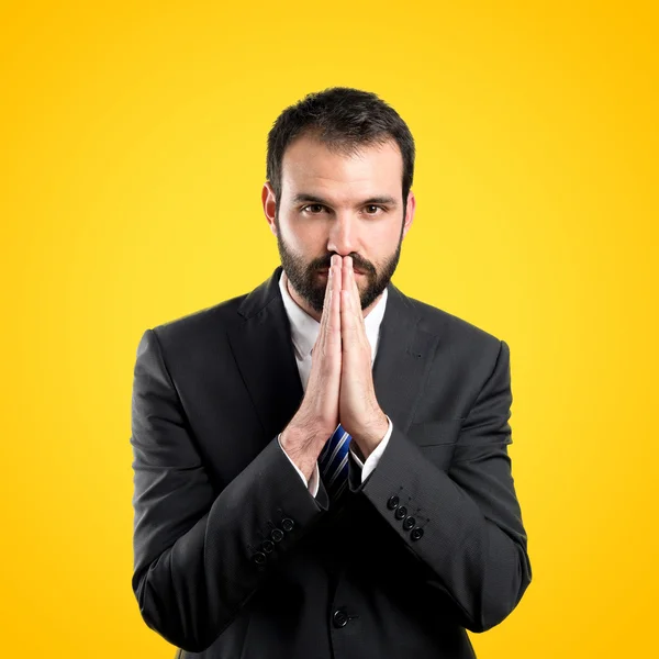 Joven hombre de negocios suplicando sobre fondo amarillo — Foto de Stock