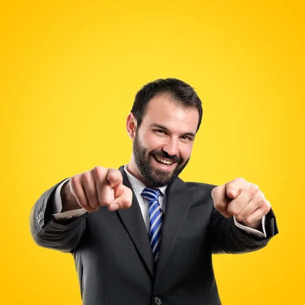 Empresario apuntando al frente sobre fondo amarillo —  Fotos de Stock