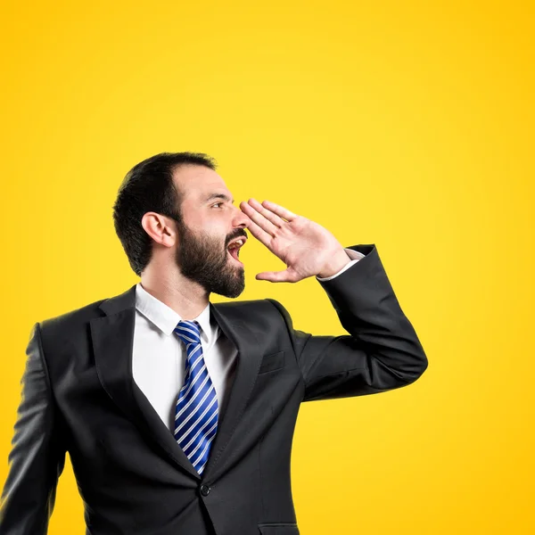 Jovem empresário gritando sobre fundo amarelo — Fotografia de Stock