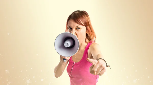 Rödhårig tjej skrika med en megafon över ockra bakgrund — Stockfoto
