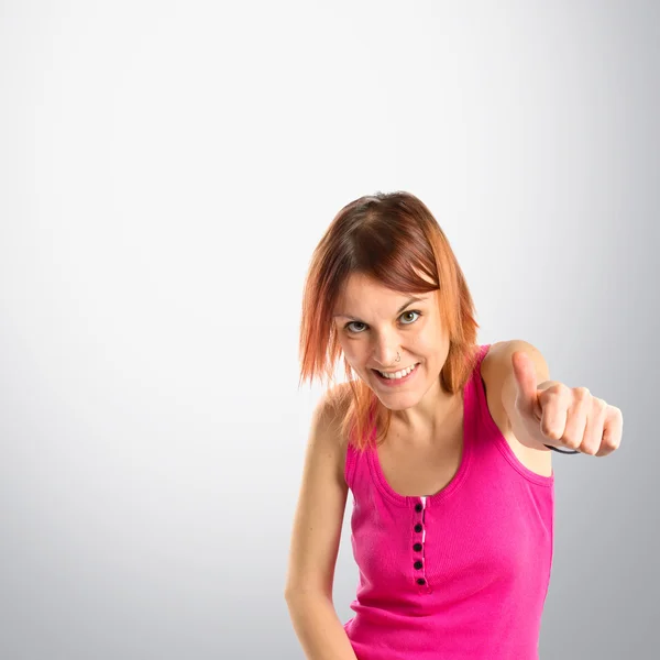 Pretty young girl with thumbs up over grey background — Stock Photo, Image