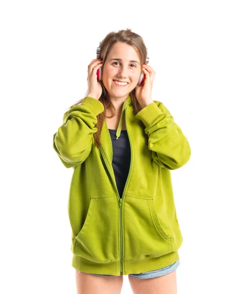 Chica joven escuchando música sobre fondo blanco — Foto de Stock