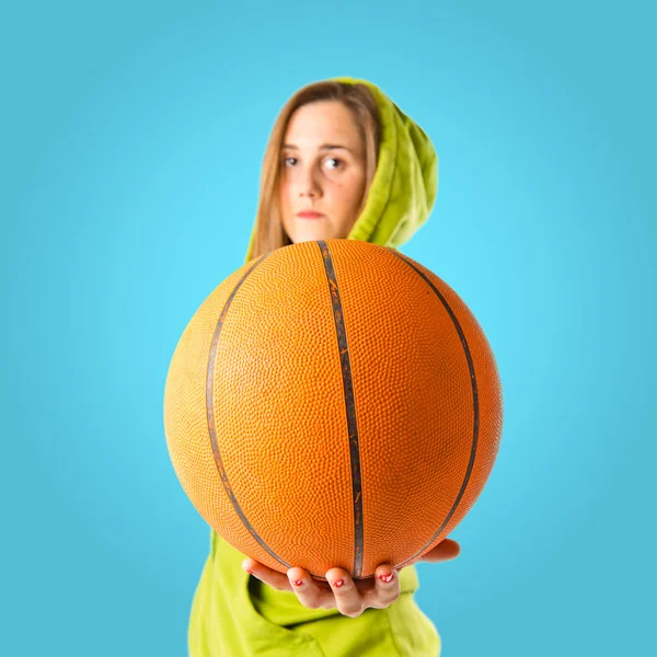 Menina loira jogando basquete sobre fundo azul — Fotografia de Stock