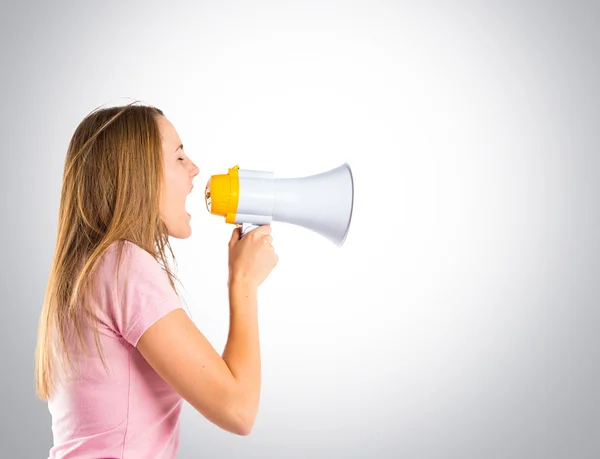 Blonde fille criant avec un mégaphone sur fond gris — Photo