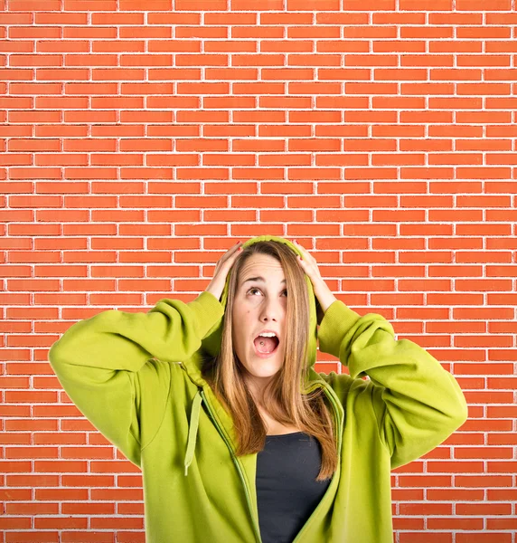 Young girl doing surprise gesture over bricks background — Stock Photo, Image