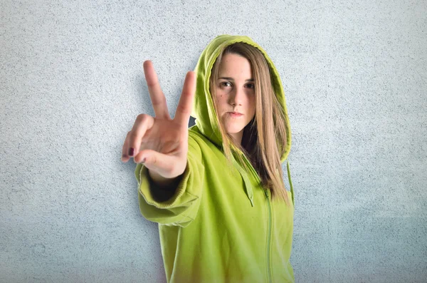 Girl doing victory gesture over textured background — Stock Photo, Image