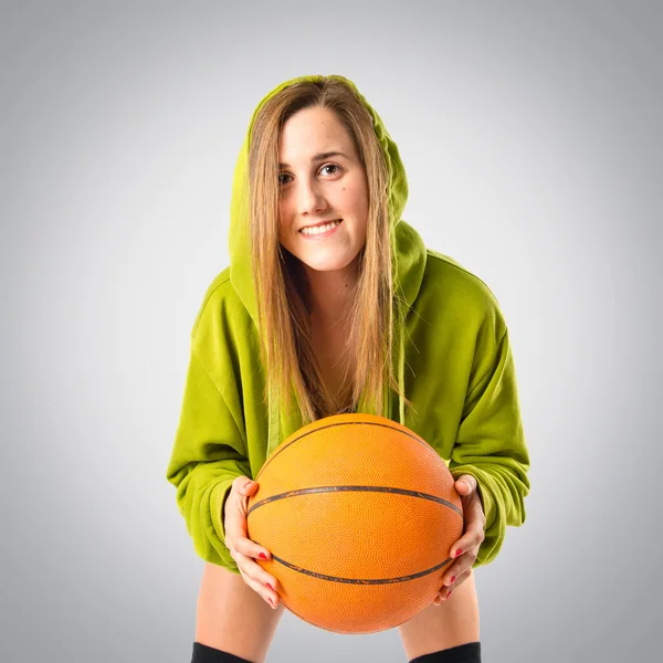 Блондинка, играющая в баскетбол на сером фоне — стоковое фото