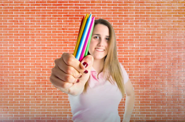 Chica rubia sosteniendo lápices de colores sobre ladrillos de fondo —  Fotos de Stock