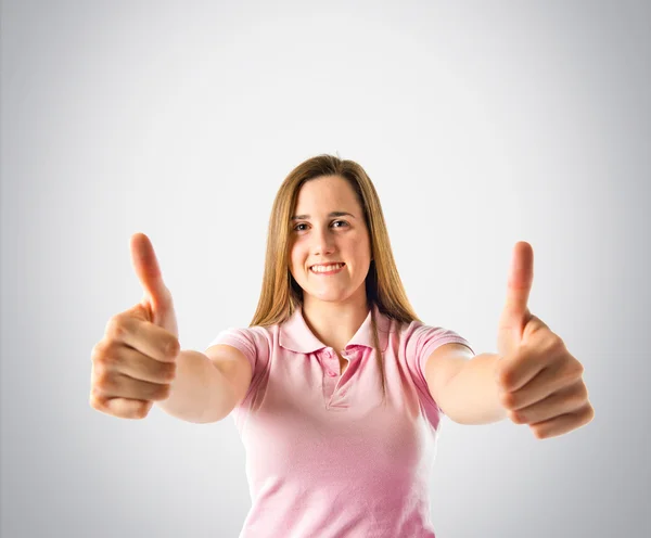Young girl making Ok sign over grey background — Stock Photo, Image