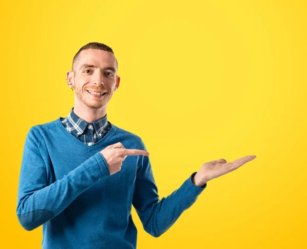 Hombre sosteniendo algo sobre fondo amarillo —  Fotos de Stock