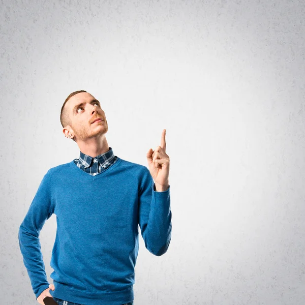 Young man pointing up over grey background — Stock Photo, Image