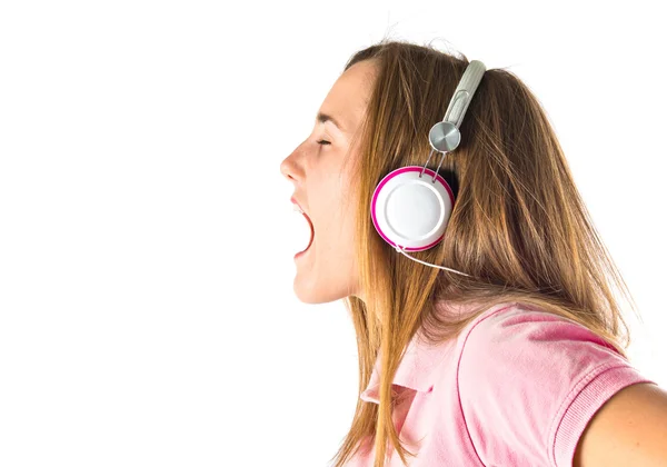 Joven chica rubia escuchando música sobre fondo blanco — Foto de Stock