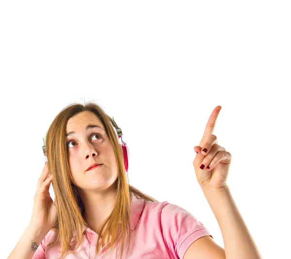 Joven chica rubia escuchando música sobre fondo blanco — Foto de Stock