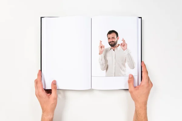 Νεαρός άνδρας με τα δάχτυλά του, διασχίζοντας εκτυπώνονται σε βιβλίο — Φωτογραφία Αρχείου