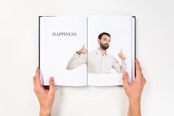 Young man with thumbs up printed on book — Stock Photo, Image