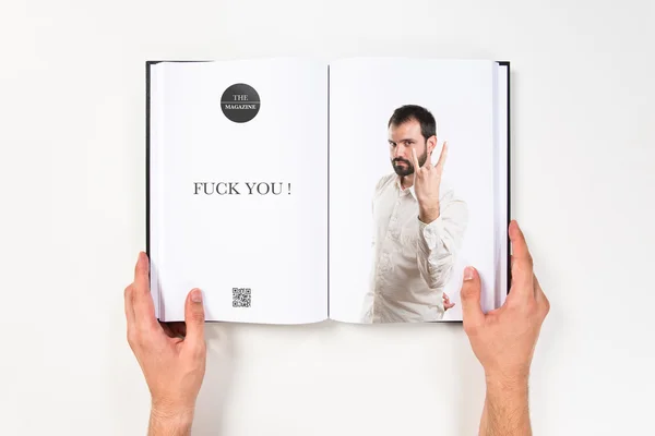 Young man doing the horn sign printed on book — Stock Photo, Image