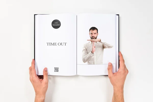 Young man doing the timeout sign printed on book — Stock Photo, Image