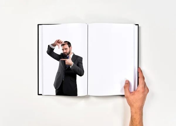 Mladý podnikatel dělá znak rámu vytištěny na knihu — Stock fotografie