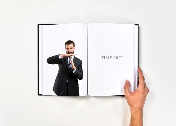 Jeune homme faisant le signe timeout imprimé sur le livre — Photo
