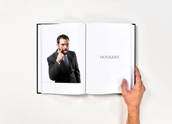 Jeune homme d'affaires faisant une moquerie imprimée sur le livre — Photo