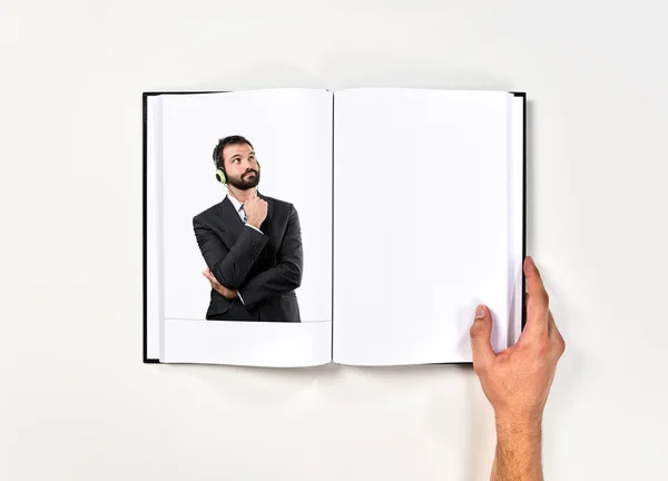 Joven empresario escuchando música impresa en libro —  Fotos de Stock