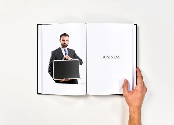 Young businessman with his briefcase printed on book — Stock Photo, Image