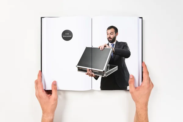 Молодий бізнесмен відкриває свій портфель, надрукований на книзі — стокове фото