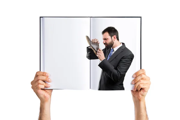 Jóvenes empresarios oliendo sus zapatos impresos en un libro — Foto de Stock