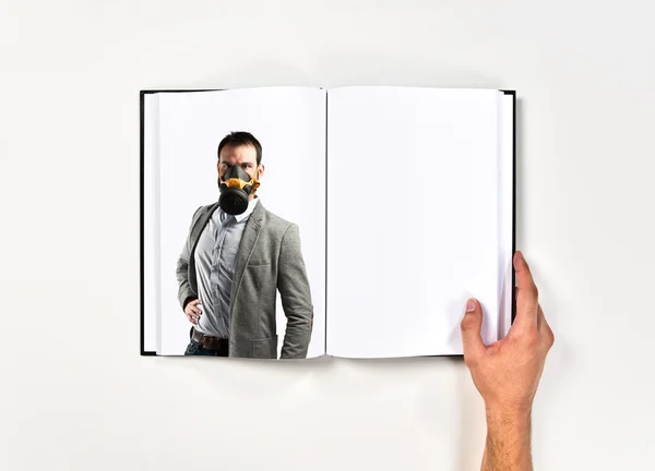 Jungunternehmer mit Gasmaske auf Buch gedruckt — Stockfoto