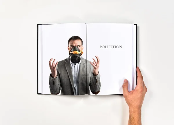 Jungunternehmer mit Gasmaske auf Buch gedruckt — Stockfoto