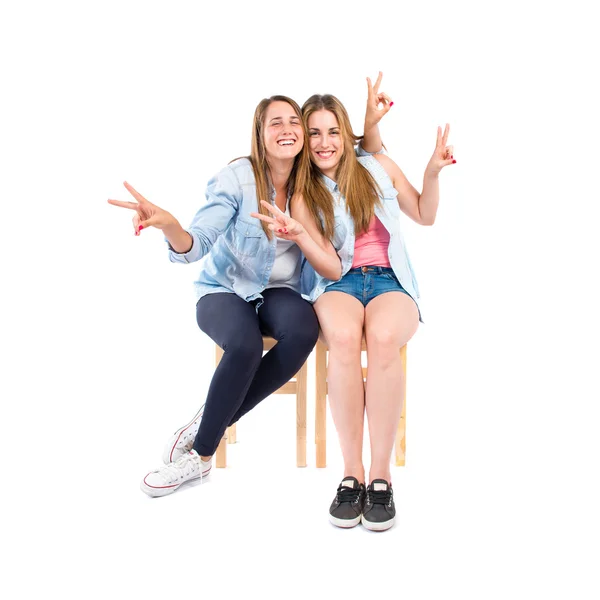 Sisters doing victory gesture over white background — Stock Photo, Image