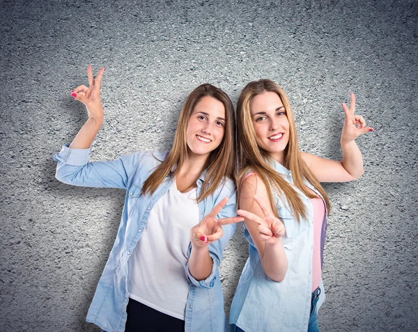 Girls doing victory gesture over textured background — Stock Photo, Image