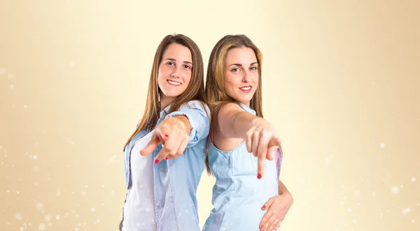Girls pointing to the front over ocher background — Stock Photo, Image