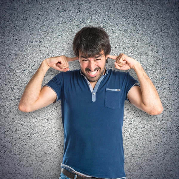 Man covering his ears over textured background — Stock Photo, Image