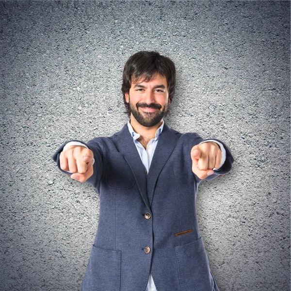 Businessman pointing to the front over textured background — Stock Photo, Image