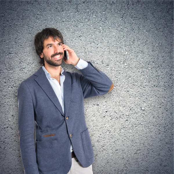 Hombre guapo hablando con móvil sobre fondo texturizado — Foto de Stock