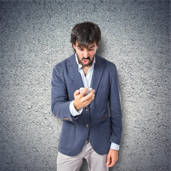 Wütender Mann spricht mit Handy über strukturierten Hintergrund — Stockfoto