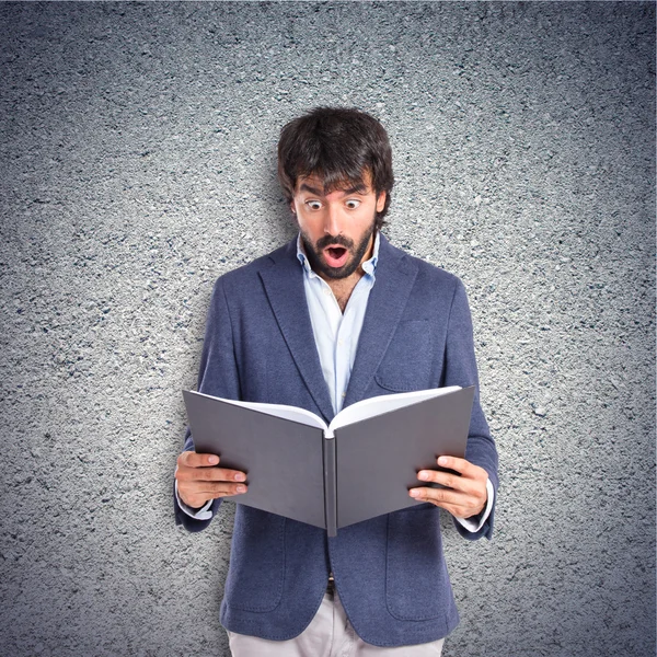 Hombre sorprendido leyendo un libro sobre fondo texturizado — Foto de Stock