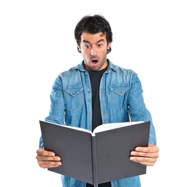 Hombre sorprendido leyendo un libro sobre fondo blanco — Foto de Stock