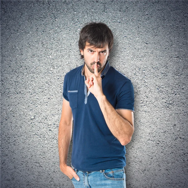 Man making silence gesture over textured background — Stock Photo, Image