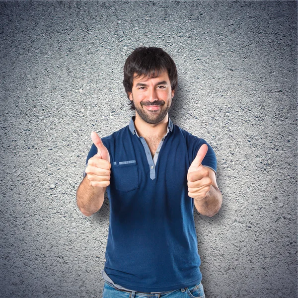 Hombre con pulgar hacia arriba sobre fondo texturizado —  Fotos de Stock