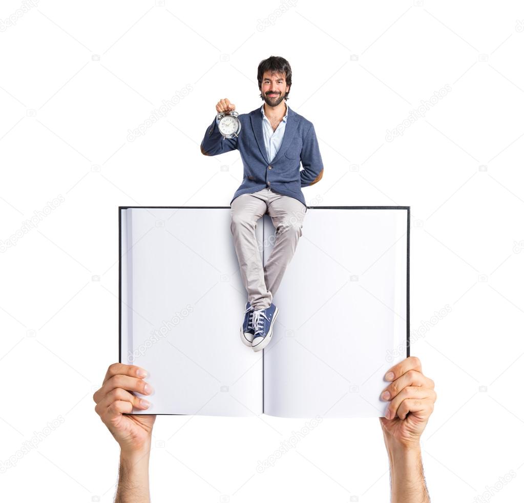 Man holding a clock sitting on book