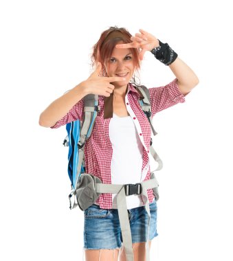 backpacker focusing with her fingers on a white background