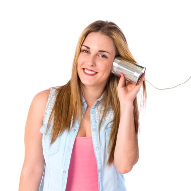 Beyaz arka plan üzerinde bir teneke telefondan dinleme kız