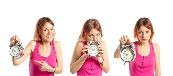 Vážné rusovláska dívka drží hodiny nad bílým pozadím — Stock fotografie
