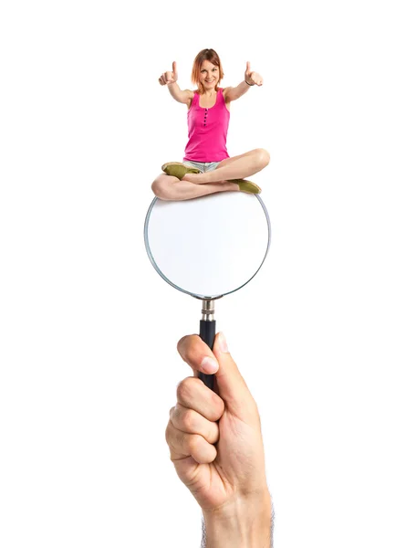 Pretty young girl with thumbs up  sitting on loupe — Stock Photo, Image