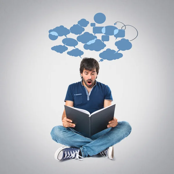 Hombre leyendo un libro sobre fondo gris — Foto de Stock