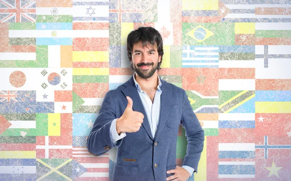 Hombre guapo con el pulgar arriba sobre el fondo de la bandera — Foto de Stock