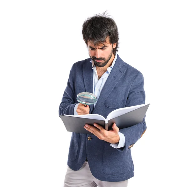 Empresario con loupe reding un libro sobre fondo blanco — Foto de Stock