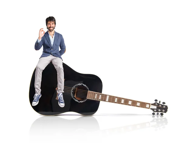 Man holding a clock sitting on guitar — Stock Photo, Image